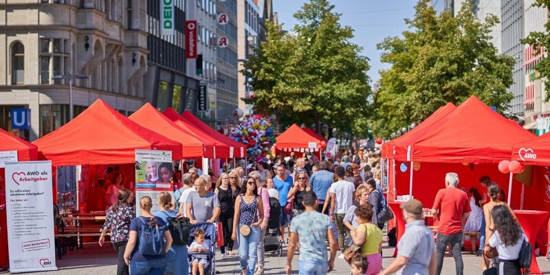 Marktszene vor einem weißen Gebäude mit braunem Dach,...