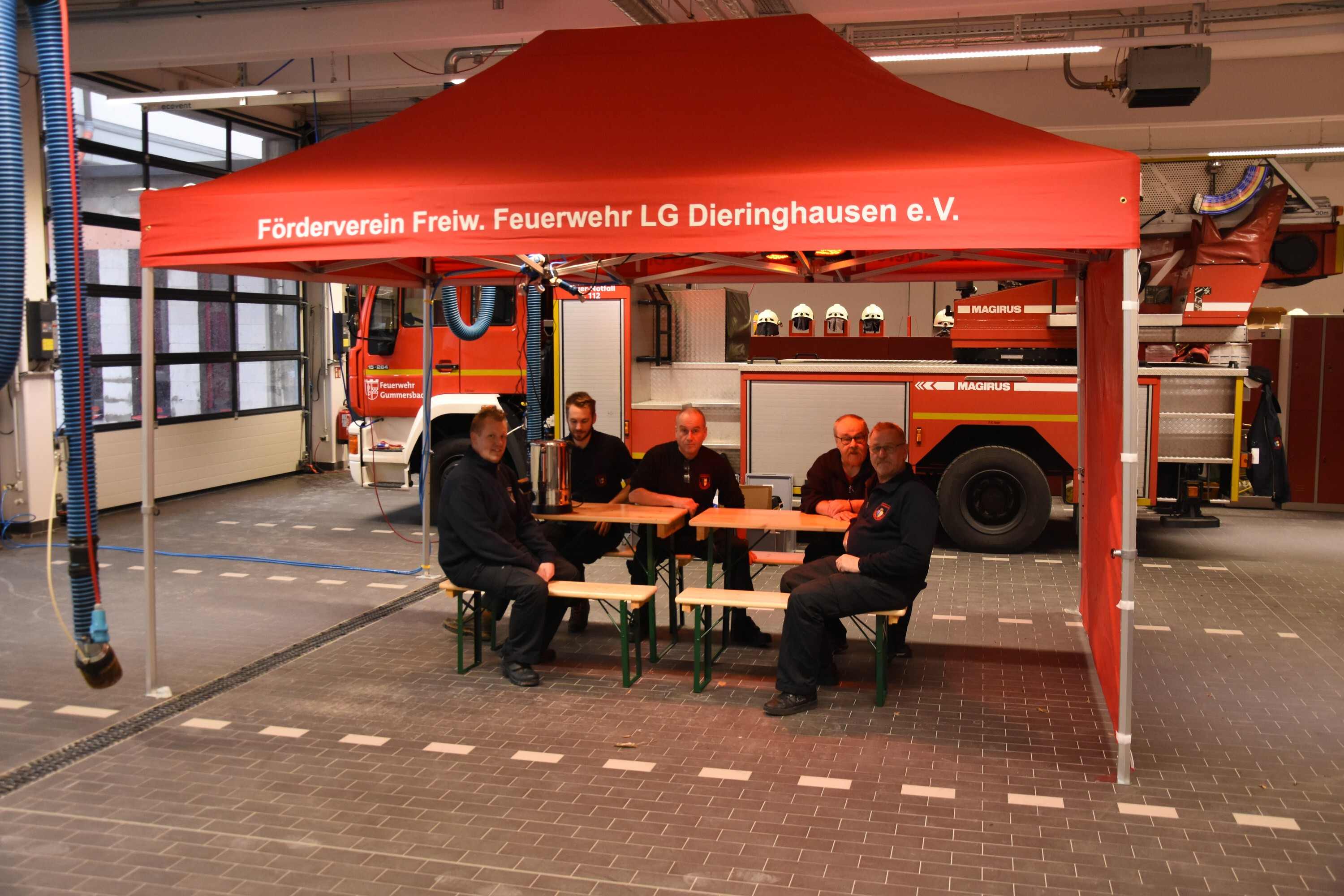 Feuerwehrleute sitzen an Bierzeltgarnituren unter dem Duratent Faltpavillon