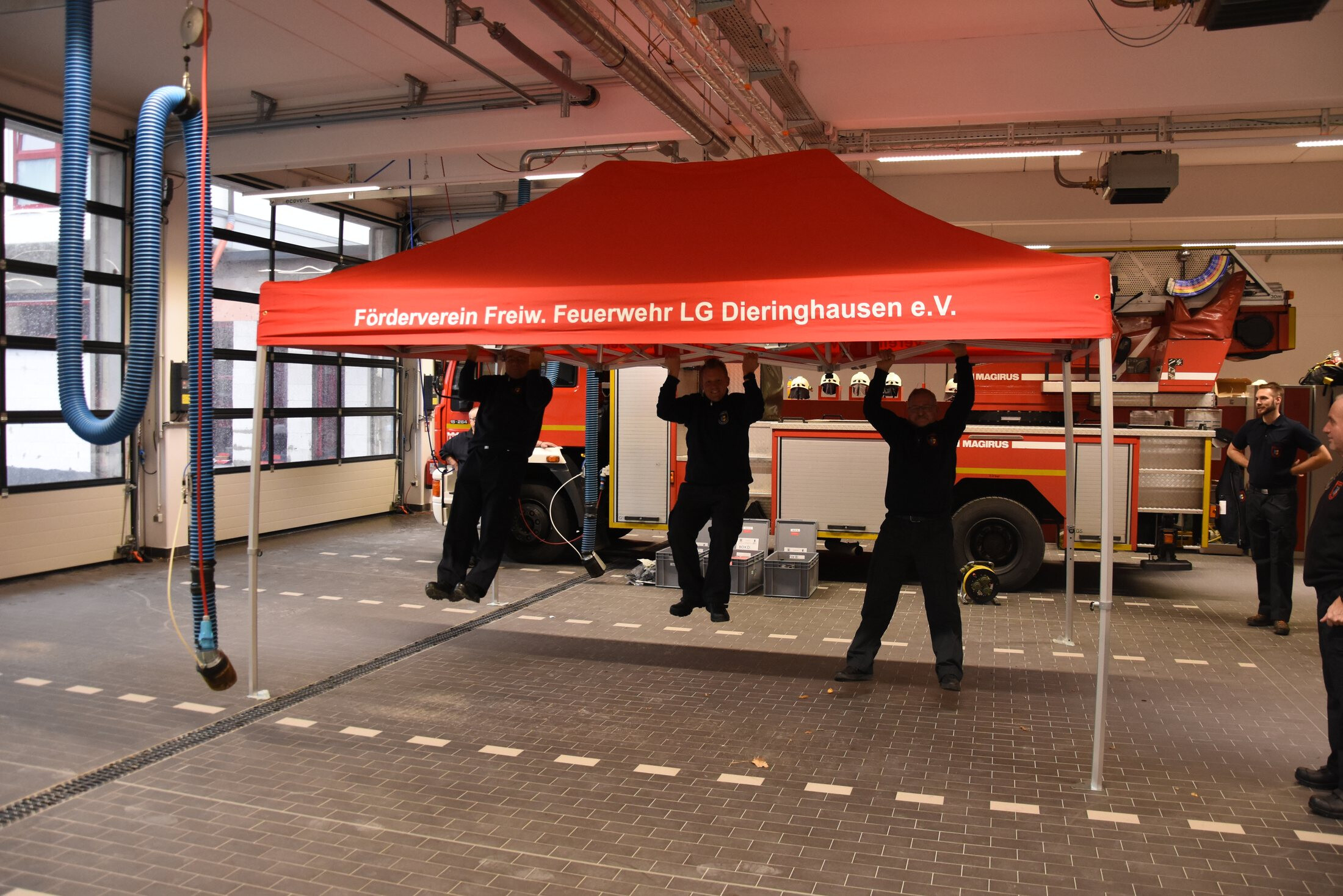 Vier Personen heben das Dach des Duratent Hexa50 in der Fahrzeughalle an